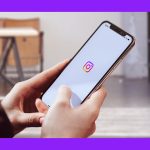 677bf47e6a21714f5ea59561_A person using a cellphone showing the Instagram logo with a white background